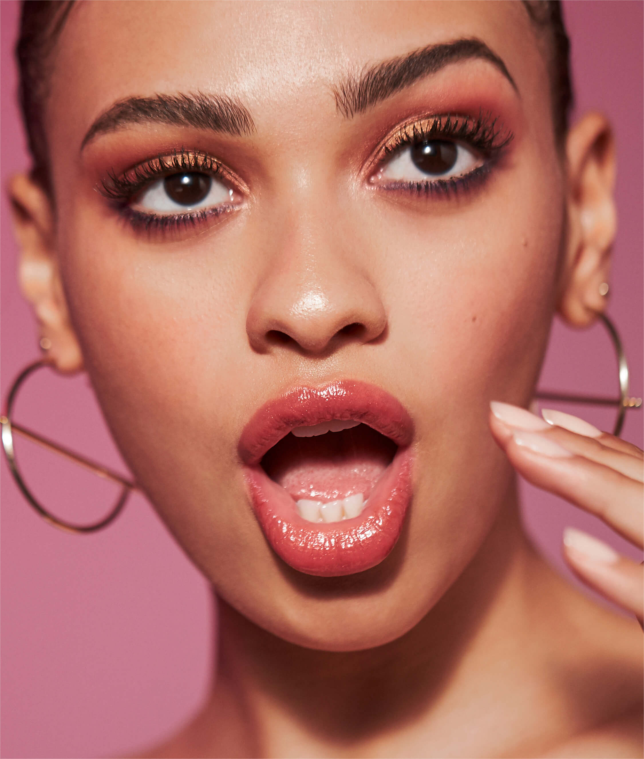 Woman with red lipstick holding silver hoop earrings